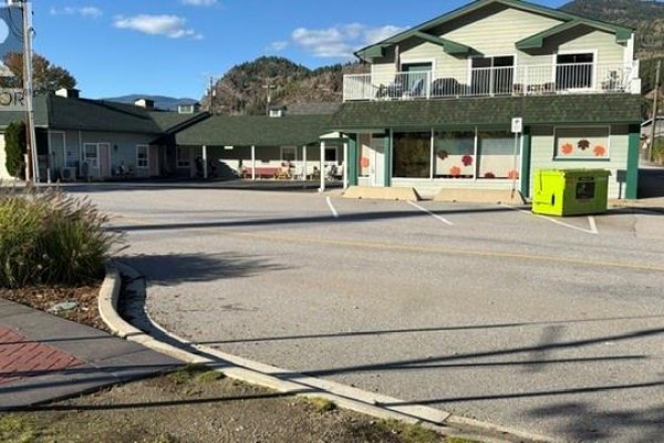 Exterior of a commercial building with a large parking lot and green accents on the facade. - 1717 Columbia Avenue, Trail
