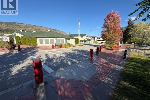 Street view of a commercial building with red and grey brick paving and red bollards. - 1717 Columbia Avenue, Trail