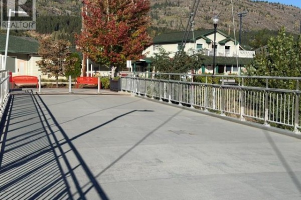 A pedestrian bridge with silver railings and concrete walkway in front of buildings. - 1717 Columbia Avenue, Trail