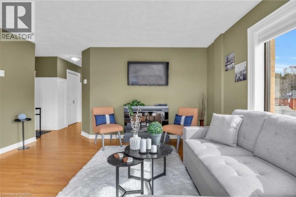 Living room with a grey sofa, orange chairs, coffee tables, and a television. - 1717 2nd Avenue E Unit# 505, Owen Sound