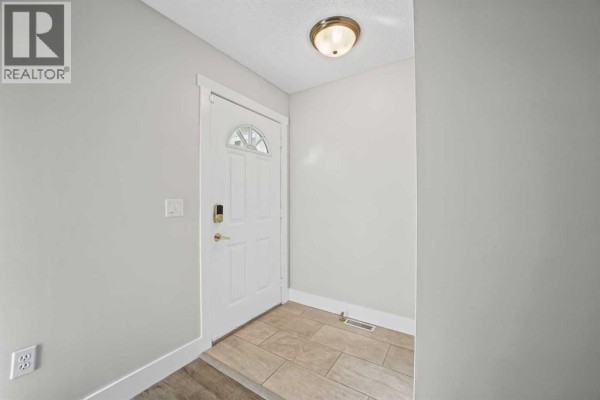 Interior view of the entrance with a white door, tiled floor, and neutral gray walls. - 1719 17 Street, Didsbury