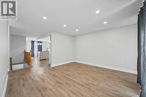 Open concept living area with light wood laminate flooring and neutral gray walls. - 1719 17 Street, Didsbury