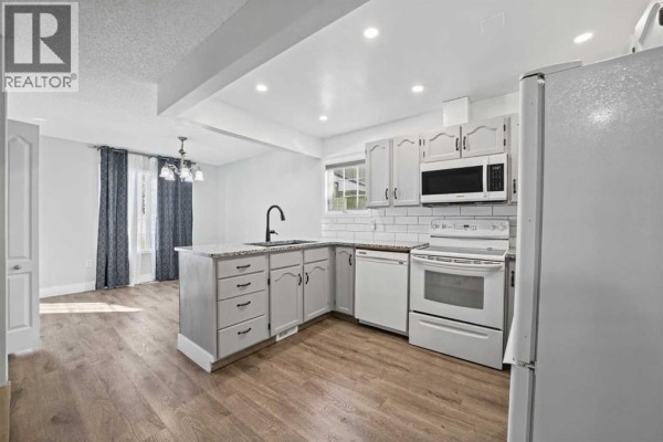 Kitchen and dining area with light wood floors, gray cabinets, and granite countertops. - 1719 17 Street, Didsbury