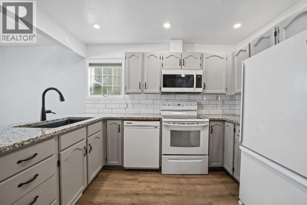 U-shaped kitchen with light gray cabinets, white subway tile backsplash, and granite countertops. - 1719 17 Street, Didsbury