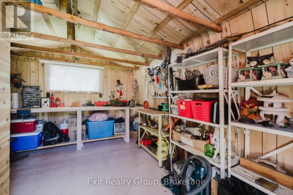Interior of shed with wooden walls, multiple shelves stocked with tools and storage bins. - 172 - 63 Whites Road, Quinte West