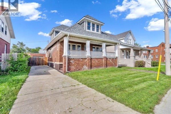 View of a brick house from the side, showing the front porch and a grass yard. - 172 Giles Boulevard, Windsor