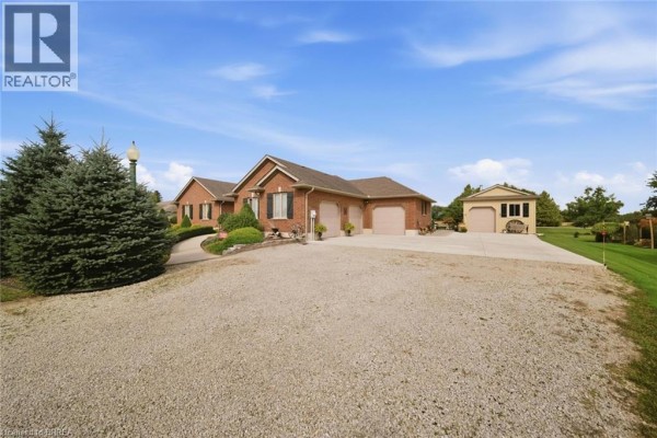 Side view of brick bungalow with attached three-car garage and detached garden shed. - 172 Highway 53, Cathcart