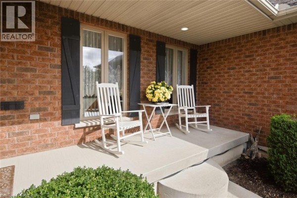 Front porch with two white rocking chairs, a small white table, and yellow flowers. - 172 Highway 53, Cathcart