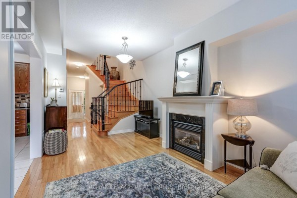 Living room with a fireplace, hardwood floors, and a staircase with black railings. - 172 Lauderdale Drive, Vaughan