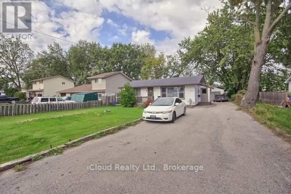 Side exterior view of the bungalow with a driveway, grass lawn, and neighboring houses. - 172 Silas Boulevard, Georgina