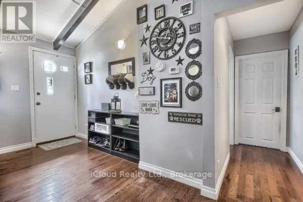 Foyer with grey walls, dark wood floors, a coat rack, shoe storage unit, and decorative wall clock. - 172 Silas Boulevard, Georgina