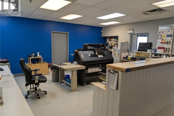 Office area with a large format printer, desk, chair, and blue accent wall. - 1720 Bishop Street N Unit# 3, Cambridge