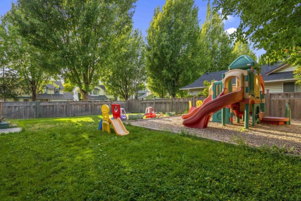 A backyard playground with slides and various children's toys on a sunny day. - 17209 62a Avenue, Surrey