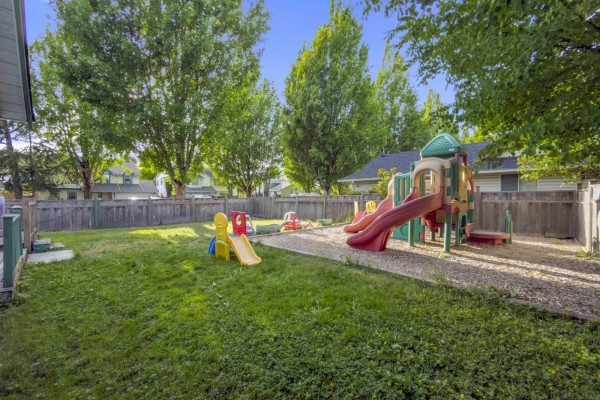 Backyard playground with slides and children's toys, surrounded by a wooden fence. - 17209 62a Avenue, Surrey