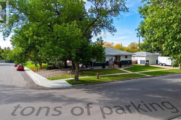 A bungalow house with a white and dark blue exterior, surrounded by trees and grass. - 1721 2b Avenue N, Lethbridge