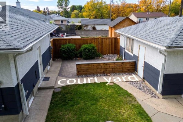 A backyard with a paved patio, a wooden planter box, and two garages. - 1721 2b Avenue N, Lethbridge