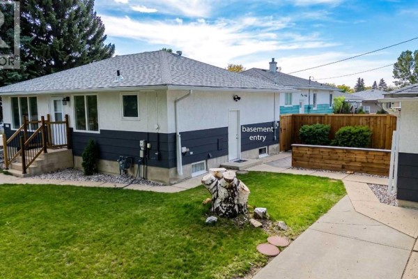 A side view of a bungalow house with a basement entrance and a wooden fence. - 1721 2b Avenue N, Lethbridge