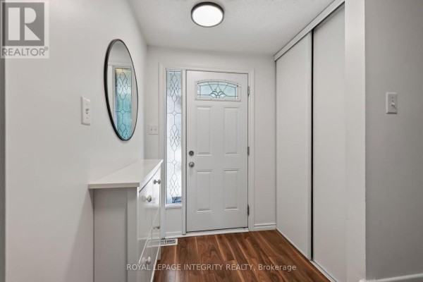 Foyer with white walls, a white door with stained glass, a mirror, and a console table. - 1723 Lafrance Drive, Ottawa