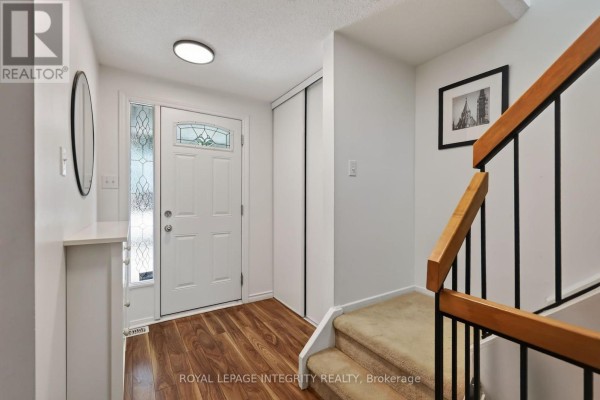Foyer with a carpeted staircase leading upstairs, a white door, and wood-look flooring. - 1723 Lafrance Drive, Ottawa
