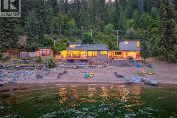 Front view of the home from the water, showcasing the beach, decks, and surrounding forest. - 1726 31 Highway, Queens Bay