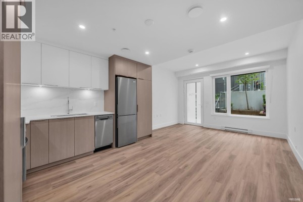 Open concept living area with a modern kitchen and wood floors, leading to a patio. - 1726 Templeton Drive, Vancouver