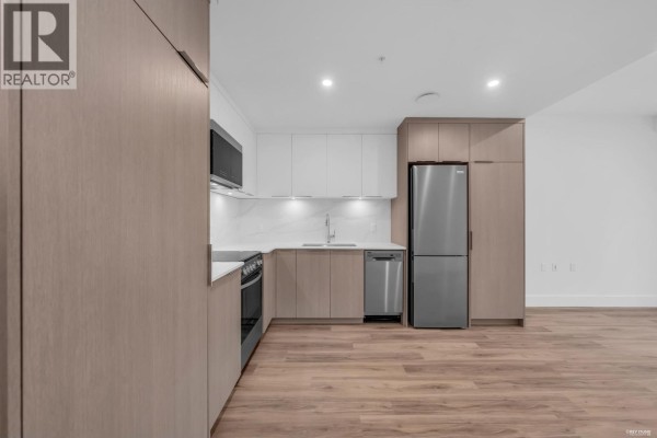 Kitchen area with light wood and white cabinetry, stainless steel appliances, and light wood floors. - 1726 Templeton Drive, Vancouver