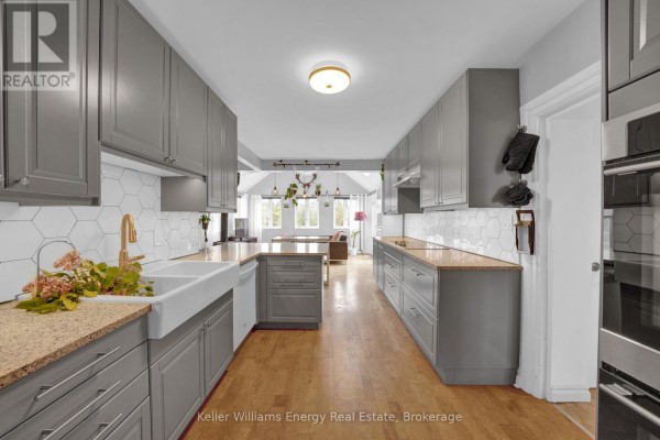 Bedroom with a queen bed, large windows, and a ceiling fan overlooking a field. - 1727 County Rd 14 Road, Prince Edward County