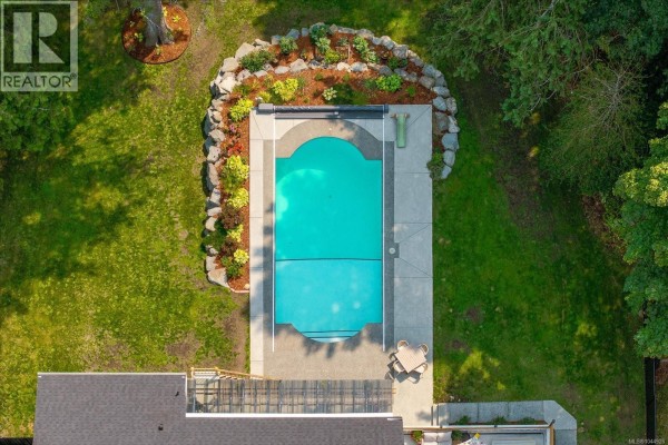 Overhead view of a rectangular swimming pool surrounded by concrete and landscaping. - 1728 Extension Rd, Nanaimo