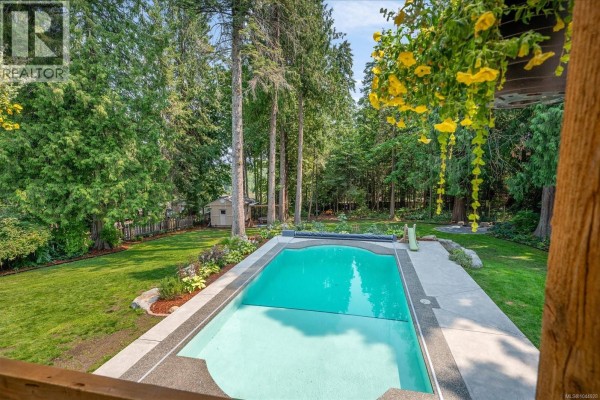 View of an in-ground swimming pool from a wooden deck. - 1728 Extension Rd, Nanaimo