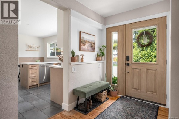 Interior entryway with wooden double doors, bench, and view to kitchen. - 1728 Extension Rd, Nanaimo