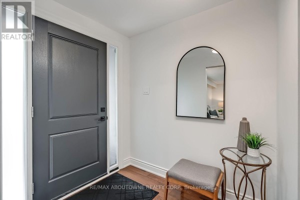 Entryway with grey door, wood floor, bench, round mirror, and console table. - 173 Arichat Road, Oakville