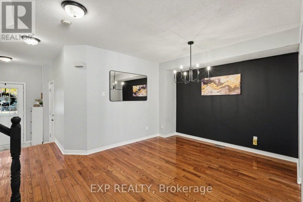 Living and dining area with hardwood floors, a black accent wall, modern mirror, and chandelier. - 173 Beatrice Drive, Ottawa