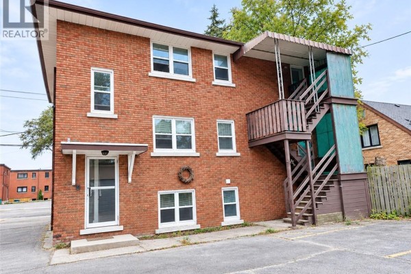 Rear exterior of the brick apartment building showing an entrance door and external staircase. - 173 Blucher Street Unit# 1, Kitchener
