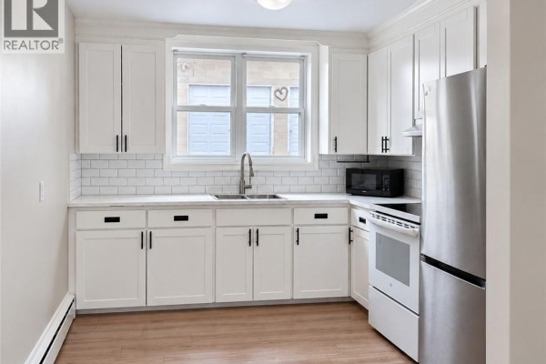 A bright white kitchen with subway tile backsplash, stainless steel appliances, and light wood floors. - 173 Blucher Street Unit# 1, Kitchener