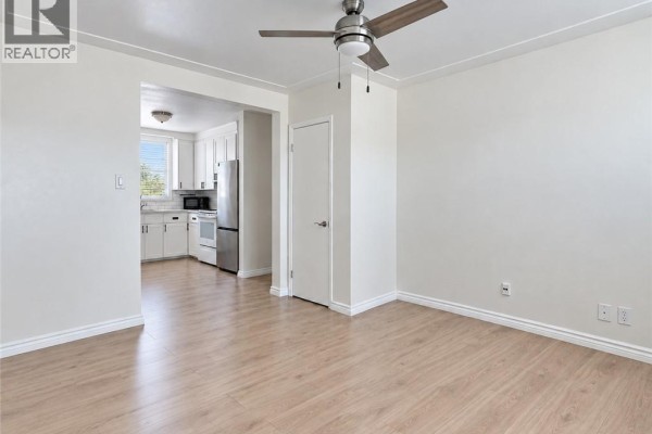 Living area with light wood floors, white walls, and a view into the white kitchen. - 173 Blucher Street Unit# 1, Kitchener