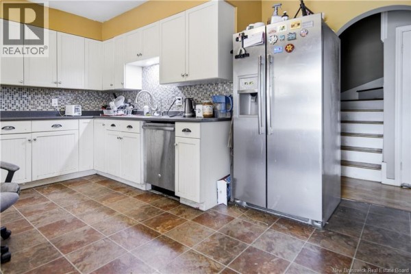 Kitchen with white cabinets, stainless steel appliances, and tiled flooring. - 173 Maple Street, Moncton
