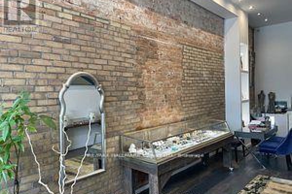 Close-up of a retail space showing an exposed brick wall, a jewelry display case, and a mirror. - 173 Queen Street E, Toronto