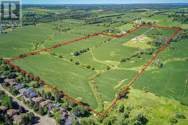 Aerial view of a large farm property outlined in red, adjacent to suburban homes. - 17305 10th  Concession, King