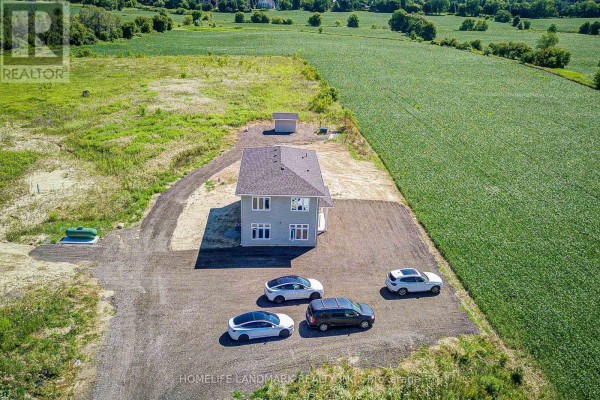 Drone view of a two-story grey house with a gravel driveway and four vehicles. - 17305 10th  Concession, King