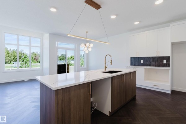 Kitchen with island, white cabinets, dark backsplash, and view of backyard. - 1731 Crossbill Lo Nw, Edmonton