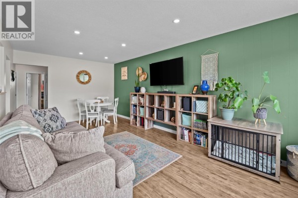 Bedroom with a queen bed, colorful quilt, open closet, and a large wave painting. - 1735 Quilchena Avenue, Merritt