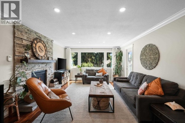 Living room with a stone fireplace, comfortable sofas, and large windows. - 1737 Anderson Way, Port Coquitlam