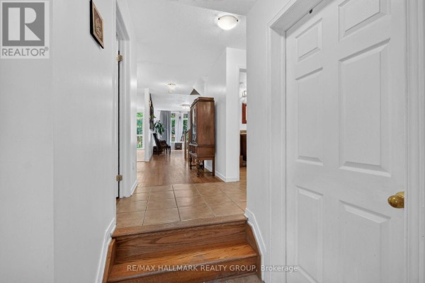 Interior hallway with hardwood steps, tiled floor, and doors to rooms. - 174 Carwood Circle W, Ottawa