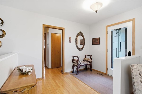 Foyer with light wood floors, white walls, and decorative bench. - 174 Foxmeadow Drive, Winnipeg