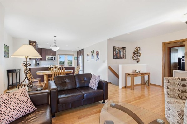 Living and dining area with hardwood floors and view of kitchen. - 174 Foxmeadow Drive, Winnipeg