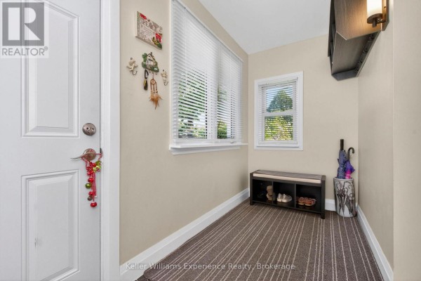 Interior entryway with a white door, bench with shoes, and striped carpet flooring. - 174 Seventh Street, Midland