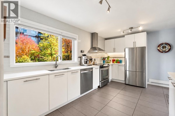 Kitchen with white cabinets, stainless steel appliances, and a large window. - 1741 Chesterfield Avenue, North Vancouver