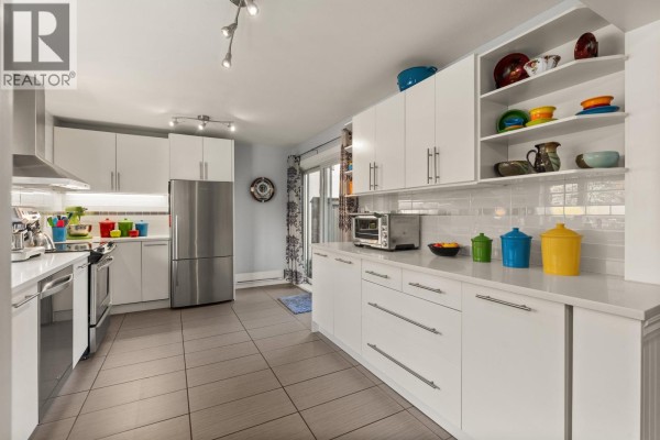Modern kitchen with white cabinetry, stainless steel appliances, and colorful decor. - 1741 Chesterfield Avenue, North Vancouver
