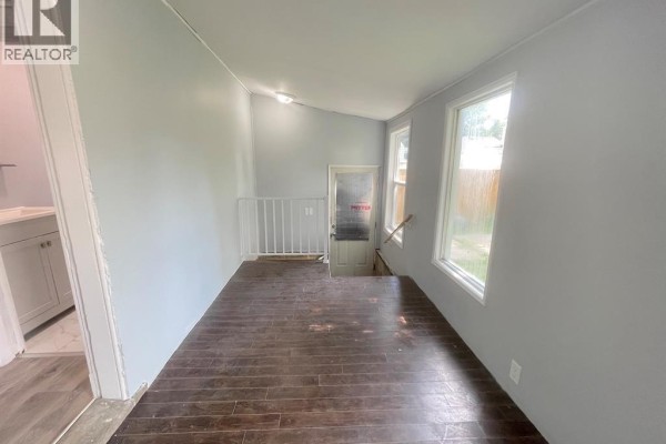 Room with dark wood laminate flooring, pale grey walls, and a doorway to stairs. - 1741 Hickory Road, Windsor