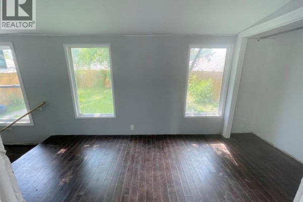 Living area with dark wood laminate flooring and two large windows with backyard view. - 1741 Hickory Road, Windsor